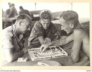 LAE AREA, NEW GUINEA. 1944-12-20. RAN PERSONNEL PLAYING CHINESE CHECKERS IN THE YMCA HUT. IDENTIFIED PERSONNEL ARE:- PETTY OFFICER C JOINER, (1); ABLE SEAMAN SCOTT, (2); SUPPLY ASSISTANT J MILLER, ..