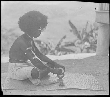 Magani scraping a coconut, Papua, ca. 1923 / Sarah Chinnery