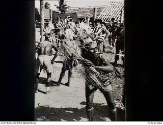 Madang, New Guinea, c. 1944-12-25. Near Headquarters, RAAF Northern Command (NORCOM), a Papuan native takes part in a traditional dance and 'sing-sing' during the Christmas season. For the purposes ..