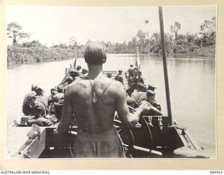 JABA RIVER AREA, BOUGAINVILLE, SOLOMON ISLANDS. 1944-12-18. 15 INFANTRY BATTALION SUPPORT TROOPS, GUIDED BY THE HELMSMAN AT THE FOREGROUND, SUCCESSFULLY NEGOTIATING THE RIVER TO ASSIST D COMPANY ..