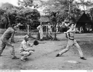 KIRIWINA, TROBRIAND ISLANDS, PAPUA. C. 1944-03. FLYING OFFICER (FO) A. F. CATT, ADELAIDE, SA, BEAUFIGHTER PILOT WITH NO. 30 SQUADRON RAAF, BATTING IN A BASEBALL GAME AGAINST MEMBERS OF THE US ..