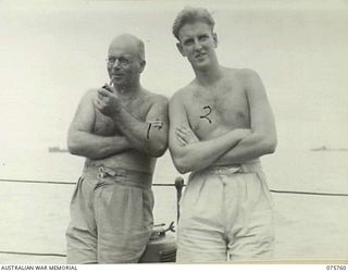 HUMBOLT BAY, NEW GUINEA. 1944-09/08. LIEUTENANT I. BARTON, RAN, CHIEF ENGINEER (LEFT) AND MIDSHIPMAN R. HILL (RIGHT) ENJOYING A SMOKE AND A BREATH OF FRESH AIR ON THE STERN OF THE RAN COVETTE, ..