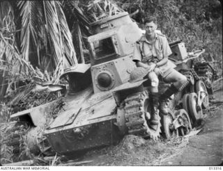 1942-10-01. NEW GUINEA. MILNE BAY. AN AUSTRALIAN MILITIA OFFICER WHO TOOK PART IN THE MILNE BAY FIGHTING, WITH AN ENEMY TYPE 95 HA-GO LIGHT TANK KNOCKED OUT DURING THE UNSUCCESSFUL JAPANESE ATTACK