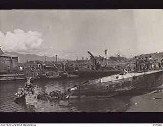 LAE, NEW GUINEA. 1943-10-12. A WRECKED JAPANESE "E" BOAT, IN THE RIGHT FOREGROUND. THE DAMAGE TO THE TAIL WAS CAUSED DURING THE ALLIED BOMBING RAIDS ON THE AREA