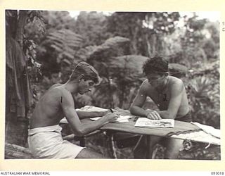 MOROKAIMORO, BOUGAINVILLE, 1945-06-06. TPR C. SAXELBY (1) AND TPR P.J. RYAN (2), READING AND WRITING AT HQ, 2/8 COMMANDO SQUADRON