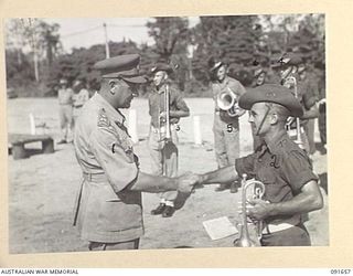 TOROKINA, BOUGAINVILLE, 1945-04-22. MAJ-GEN C.H. SIMPSON, SIGNAL OFFICER- IN- CHIEF (1), SHAKES HANDS WITH SERGEANT W. FISHER, BAND SERGEANT, 31/51 INFANTRY BATTALION (2). THE BAND TOOK PART IN THE ..