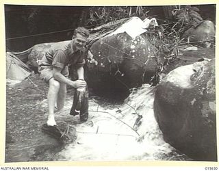 1943-08-30. NEW GUINEA. LANCE CORPORAL J.L. BRITNELL, OF BALLARAT VICTORIA, DOING HIS WASHING IN A MOUNTAIN STREAM AT BUIGAP. (NEGATIVE BY H. DICK)