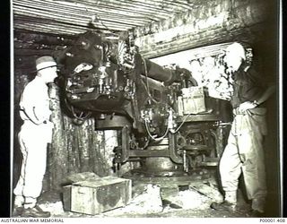 NEW IRELAND, 1945-10. AUSTRALIAN AND NEW ZEALAND OFFICERS INSIDE A GUN EMPLACEMENT INSPECTING A HEAVY COASTAL GUN. (RNZAF OFFICIAL PHOTOGRAPH.)