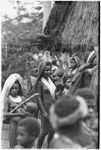 Pig festival, wig ritual, Tsembaga: women, several holding small infants, gather near dance ground to see wigged men emerge