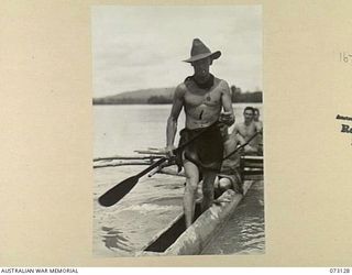 ALEXISHAFEN, NEW GUINEA. 1944-05-10. PRIVATE C. GLENNON, 30TH INFANTRY BATTALION (1), WEARS A LAP-LAP OF JAPANESE SILK WHILE PADDLING A NATIVE CANOE