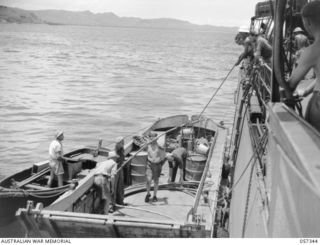 BOERA POINT, NEW GUINEA. 1943-10-01. TRANSFERRING THE BEACH END OF THE NEW SUBMARINE CABLE FROM THE SS MERNOO TO A BARGE. THIS SECTION OF THE CABLE IS SPECIALLY PREPARED TO PROTECT IT FROM THE SUN ..