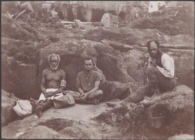Three men sitting on the landing rocks of Merelava, Banks Islands, 1906 / J.W. Beattie