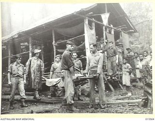 1943-08-16. NEW GUINEA. MOUNT TAMBU. A WOUNDED AMERICAN SOLDIER BEING CARRIED FROM THE ADVANCED DRESSING STATION AT HOUSE BANANA PRIOR TO BEING HANDED OVER TO THE NATIVE BEARERS, KNOWN AS ..