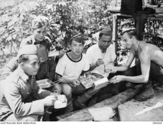 RABAUL, NEW BRITAIN, 1945-09-11. PRIVATE W. SKEELS, A MEMBER OF THE PRISONER OF WAR RECEPTION COMMITTEE, HANDS FOOD TO A SMALL GROUP OF JAPANESE SERVICEMEN. THE JAPANESE HAD BEEN INTERNED ABOUT 15 ..