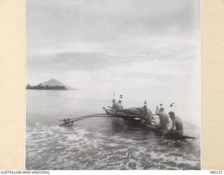 DUGUMUR, NEW GUINEA. 1944-07. THE TRANSFER OF PATIENTS FROM THE 2/15TH FIELD AMBULANCE, AUSTRALIAN ARMY MEDICAL CORPS BY A NATIVE LAKATOI TO A MEDICAL LAUNCH. MANAM ISLAND, A LIVE VOLCANO, IS SEEN ..