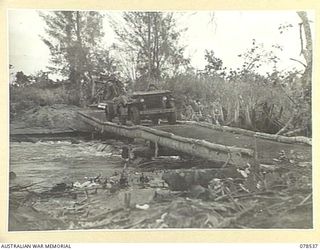 BOUGAINVILLE ISLAND, 1945-01-20. A SALVATION ARMY JEEP BRINGING TEA AND BISCUITS TO TROOPS OF THE 42ND INFANTRY BATTALION IN THE MAWARAKA VILLAGE, CROSSING THE LOG AND WIRE BRIDGE OVER THE ..