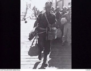 SYDNEY, NSW. 1946-05-09. NX42824 CORPORAL C. BATES, 2/10TH INFANTRY BATTALION, RETURNING HOME, ON THE WHARF CARRYING HIS STRETCHER AFTER DISEMBARKING FROM THE TROOPSHIP DUNTROON AFTER HER ARRIVAL ..