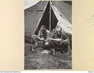 CAPE WOM, WEWAK AREA, NEW GUINEA. 1945-09-15. PRIVATE W.R. DEAN (1) AND PRIVATE A.C. STRINGER, MEMBERS OF HEADQUARTERS 6 DIVISION, POLISHING THEIR BOOTS