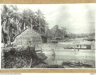 TERAPO, NEW GUINEA, 1943-09-16. VIEW OF THE WATERFRONT SHOWING AUSTRALIAN LANDING CRAFT VEHICLES TIED UP AT THE WHARF AND AN ANTI-AIRCRAFT MACHINE GUN PIT. (LEFT FOREGROUND)