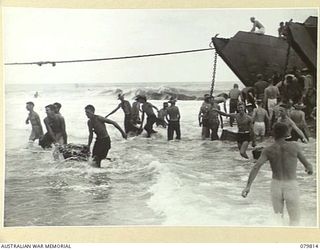 TOKO, BOUGAINVILLE, SOLOMON ISLANDS. 1945-03-20. TROOPS OF THE 2ND FIELD REGIMENT, ROYAL AUSTRALIAN ARTILLERY MANHANDLING AMMUNITION THROUGH HEAVY SURF FROM AN AMERICAN LCT (LANDING CRAFT TANK)