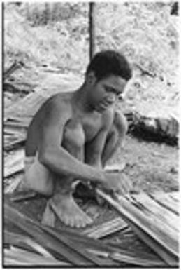 Young man ties thatch panel