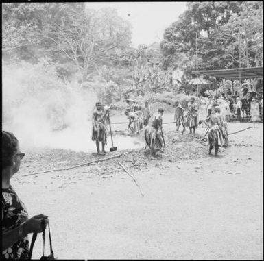 Fijian men, dressed in traditional costumes, covering the fire with soil, Fiji, 1966 / Michael Terry