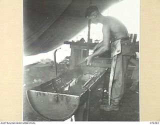 LAE, NEW GUINEA. 1944-09-27. A FITTER TROPIC PROOFING A .303 LEE ENFIELD RIFLE AT THE 43RD ORDNANCE DEPOT