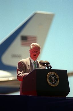 President William Jefferson Clinton gives a speech from the lectern on the runway just after his arrival for the commemoration of the 50th anniversary of the end of World War II
