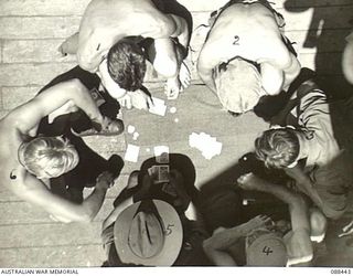 AT SEA. 1945-03-30. 2/48 INFANTRY BATTALION PERSONNEL PLAYING POKER ON THE TOP DECK ABOARD THE VAN HEUTSZ DURING THE EMBARKATION OF HEADQUARTERS 26 INFANTRY BRIGADE TO MILNE BAY. IDENTIFIED ..