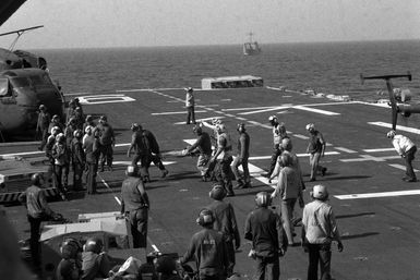 Flight deck crewmen and medical personnel carry a wounded serviceman across the flight deck of the amphibious assault ship USS GUAM (LPH 9). The serviceman was wounded during the multiservice, multinational Operation URGENT FURY, was evacuated to the GUAM aboard a US Army helicopter