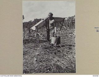 BOUGAINVILLE. 1945-05-16. GUNNER E. MCGARRY, 21 BATTERY, 2/11 FIELD REGIMENT, ROYAL AUSTRALIAN ARMY, MOVING IN WITH HIS CAMP STRETCHER AND BUCKETS AT THE GUN POSITION ALONG THE BUIN ROAD. THE ..