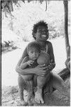 Bomagai: smiling woman with a young child who holds ball made from pig's bladder