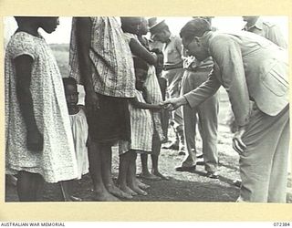 BISIATABU, NEW GUINEA. 1944-04-19. THE HONOURABLE E.J. WARD, MINISTER FOR EXTERNAL TERRITORIES IN THE AUSTRALIAN GOVERNMENT, SHAKING HANDS WITH A SMALL NATIVE GIRL AT THE ROYAL PAPUAN CONSTABULARY ..