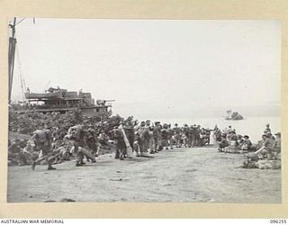 JACQUINOT BAY, NEW BRITAIN. 1945-09-09. TROOPS OF 2/1 GUARD REGIMENT FILING DOWN THE APPROACH TO A BARGE POINT FOR EMBARKATION ON HMAS MANOORA. THE MANOORA CARRIED TROOPS FOR THE OCCUPATION OF THE ..