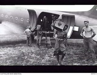 NADZAB AIRSTRIP, NEW GUINEA. 1943-09-18. NATIVES UNLOADING SUPPLIES FROM AIRCRAFT. ON THE RETURN JOURNEY WOUNDED SOLDIERS WILL BE FLOWN BACK TO BASE HOSPITALS