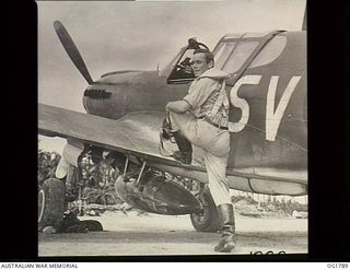 MOMOTE, LOS NEGROS ISLAND, ADMIRALTY ISLANDS. C. 1944-04. FLIGHT SERGEANT VINCENT HIGGINS, MELBOURNE, VIC, AND NO. 76 (KITTYHAWK) SQUADRON RAAF, MAKES A HASTY LEAP UP ON HIS WING TO PILE INTO HIS ..