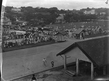 [A large crowd gathered along a main road in Tahiti]
