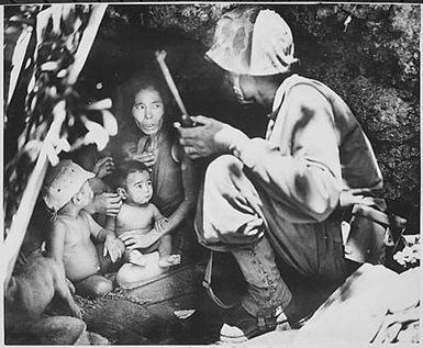 "A member of a Marine patrol on Saipan found this family of Japs hiding in a hillside cave. The mother, four children and a dog, took shelter from the fierce fighting in that area."