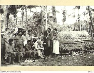 SINGORKAI, NEW GUINEA. 1944-03-19. TWO MEMBERS OF THE PAPUAN INFANTRY BATTALION STANDING GUARD OUTSIDE A PRISON BUILT FOR PRISONERS OF WAR