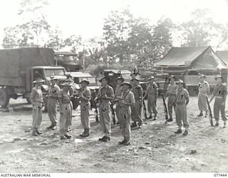 LAE BASE AREA, NEW GUINEA. 1944-12-04. VX112084 CAPTAIN A.L. KONG, OFFICER- IN- CHARGE (1) AND WX4563 WARRANT OFFICER II, K.B. JOHNSON, SECOND IN CHARGE (2) INSPECTING ARMS DURING THE MORNING ..