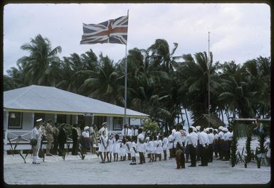 Welcoming ceremony on Palmerston Island, showing dignitaries and community members assembled beneath the Union Jack