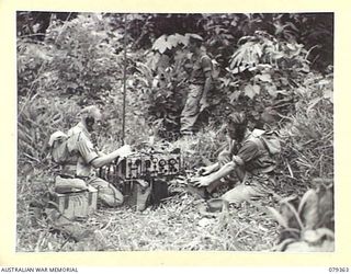 LAE, NEW GUINEA. 1945-03-11. SIGNALLERS OF THE NEW GUINEA SCHOOL OF SIGNALS OPERATING A WS22 SET AT A FICTITIOUS HEADQUARTERS