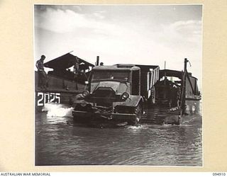 BORAM BEACH, NEW GUINEA. 1945-08-06. A TRUCK OF HEADQUARTERS COMMAND, AUSTRALIAN ARMY SERVICE CORPS, 6 DIVISION, LADEN WITH AMMUNITION COMING OFF AN AUSTRALIAN LANDING CRAFT WHICH HAS BROUGHT ..