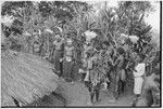 Pig festival, sacred stone house: decorated men and boys outside of house where fertility stones hang