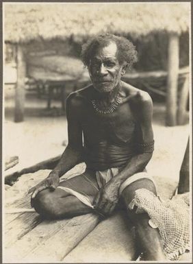 Men of Mailu [elderly man sitting on wooden deck rolling fibrous material on his thigh] Frank Hurley