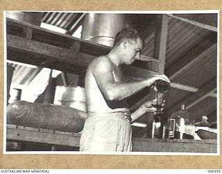 17 MILE, LALOKI RIVER, NEW GUINEA. 1943-11-22. Q144093 CORPORAL G. WARRY MIXING SYRUP FOR CORDIALS AT THE CORDIAL FACTORY ESTABLISHED AND OPERATED BY THE AUSTRALIAN DEFENCE CANTEEN SERVICE ATTACHED ..