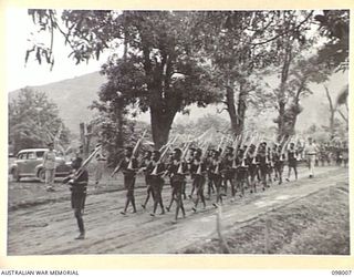 RABAUL, NEW BRITAIN. 1945-10-11. MAJOR GENERAL K.W. EATHER, GENERAL OFFICER COMMANDING 11 DIVISION, TAKING THE SALUTE FROM THE LAST PLATOON OF THE ROYAL PAPUAN CONSTABULARY AS THEY MARCH PAST THE ..