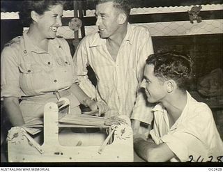 TOROKINA, BOUGAINVILLE ISLAND, SOLOMON ISLANDS. 1945-04-11. RED CROSS SENIOR SUPERINTENDENT SHEILA GRAHAM OF SYDNEY, NSW, DEMONSTRATES THE ART OF WEAVING TO 15009 WARRANT OFFICER K. DELAHUNTY OF ..