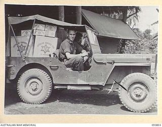 LAE AREA, NEW GUINEA, 1945-07-11. WARRANT OFFICER 2 J.D. DOOLEY, 8 MOVEMENT CONTROL GROUP, COLLECTING HAMPERS FOR THE UNIT FROM THE AUSTRALIAN COMFORTS FUND, LAE DISTRIBUTION CENTRE