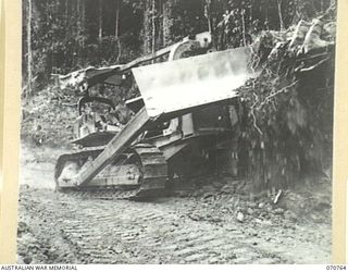 WAMPIT, NEW GUINEA. 1944-03-01. A D8 ANGLEDOZER REEFING THE BANK ABOUT 65 MILES FROM WAU ON THE WAU - LAE ROAD SECTION. THE ROAD IS IN AN OPERATIONAL AREA OF HEADQUARTERS, COMMANDER ROYAL ENGINEERS ..